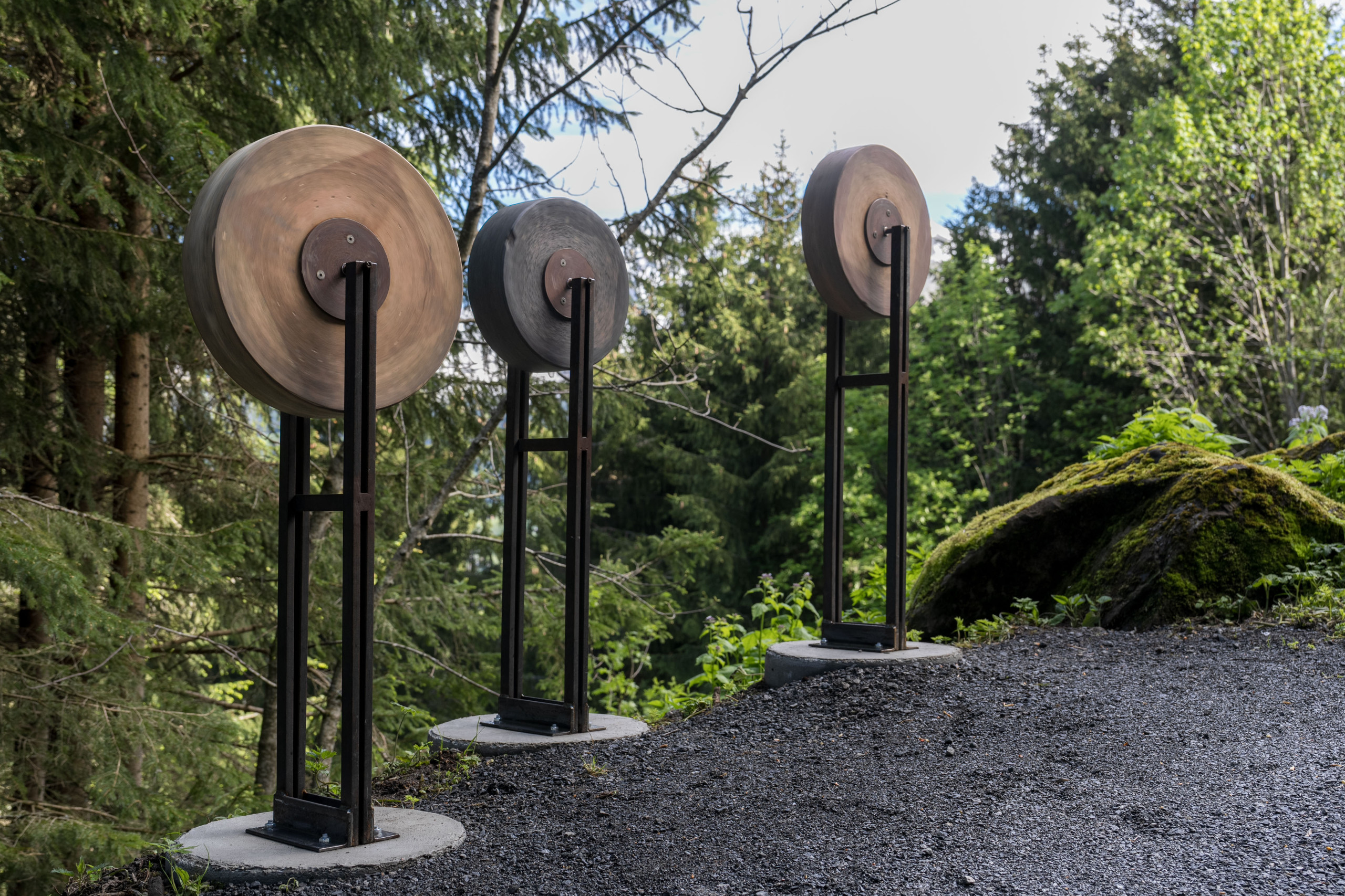 Drei mit Kieselsteinen gefüllte Tonmühlen Skulpturen stehen am Wegrand des Klangweg Toggenburg