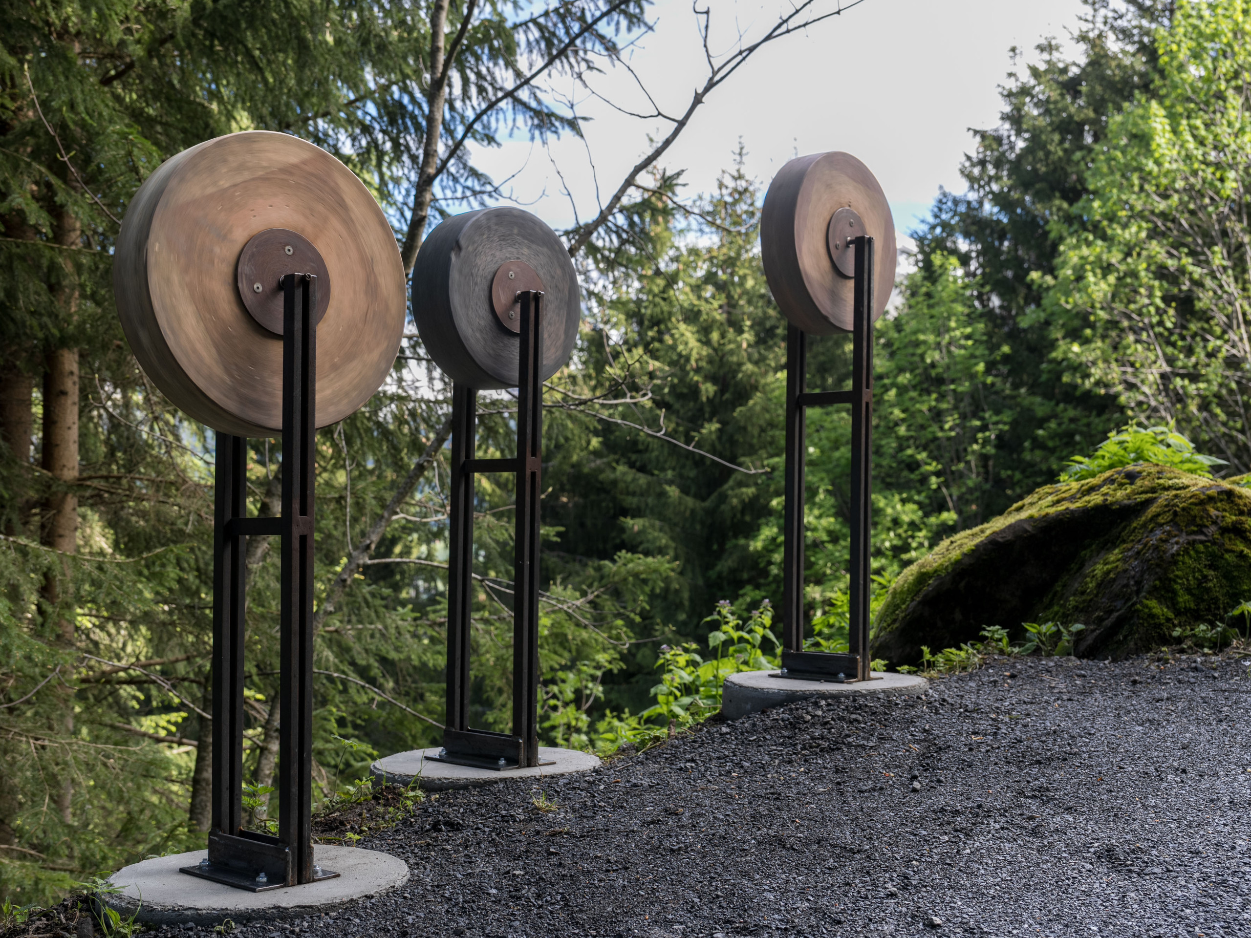 Drei mit Kieselsteinen gefüllte Tonmühlen Skulpturen stehen am Wegrand des Klangweg Toggenburg